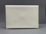 un gros plan d'un portefeuille blanc posé sur une surface grise