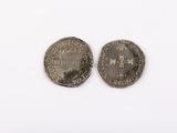 two silver coins on a white surface, one of which has a crown and the other of which is a