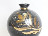a black vase with a gold leaf design on it
