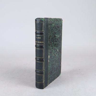 un vieux livre posé sur une table à côté d'un mur blanc