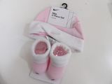 pink and white baby booties and a pink hat on a white table