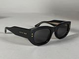 Les lunettes de soleil sont noires et ornées de clous dorés sur les branches.