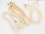 trois colliers à trois rangs de perles et une paire de boucles d'oreilles sur fond blanc