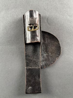 leather belt with a metal buckle on a gray surface