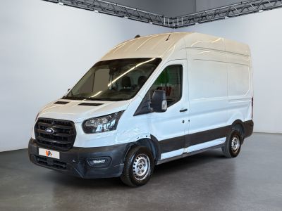 La camionnette blanche est garée dans une grande pièce au sol gris.