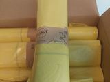 several rolls of yellow plastic are stacked in a cardboard box