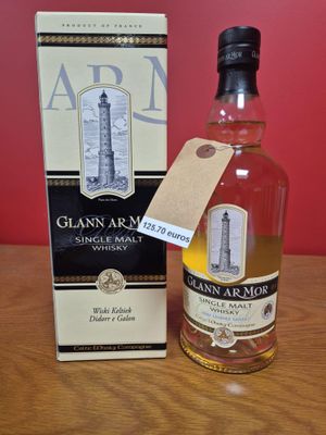 une photo montrant une bouteille de whisky posée à côté d'une boîte sur une table