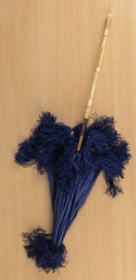 un parapluie bleu avec un manche en bambou posé sur une surface en bois