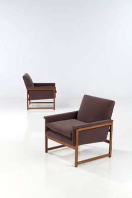 two brown chairs in a white room with a white floor