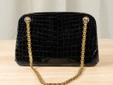 a black purse with gold chains on a wooden table