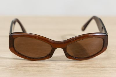 brown sunglasses on a wooden table with a white wall in the background