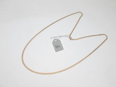 une chaîne en or à laquelle est accrochée une médaille, posée sur une surface blanche