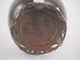 a brown vase with holes in it sitting on a white surface
