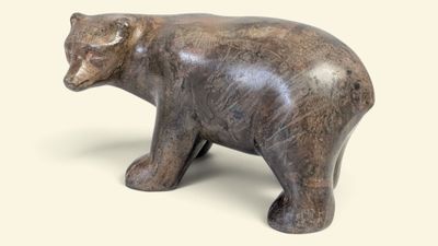 une petite statue représentant un ours sur fond blanc