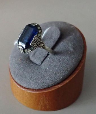 a ring with a blue stone in it sitting on a wooden box