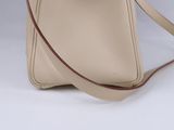 beige leather handbag with strap on white background