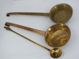 three brass measuring spoons and a measuring scale on a white surface