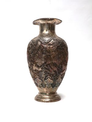 un vase en argent posé sur une surface blanche