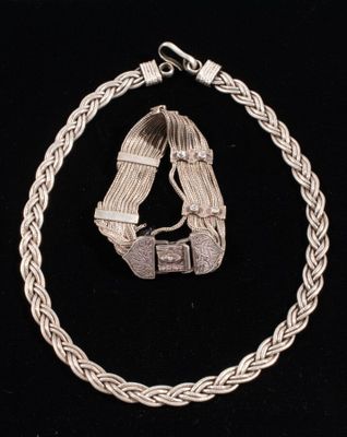 a close up of a silver bracelet with a clasp on a black background