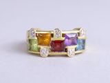 a close up of a gold ring with multi colored stones