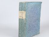 an old book sitting on top of a white table next to a white wall