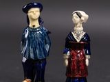 two figurines of people standing next to each other on a black surface