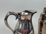 a silver pitcher sitting next to a shaker on a table