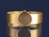 a gold wrist watch sitting on a shiny surface