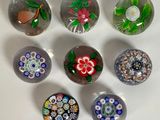 six billes de verre aux motifs variés posées sur une surface blanche
