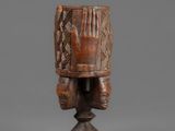 a carved wooden headdress on a pedestal with a wooden base