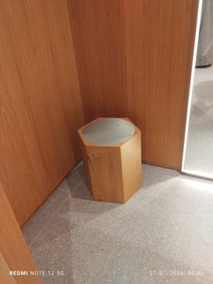 a small wooden stool in the corner of a bathroom