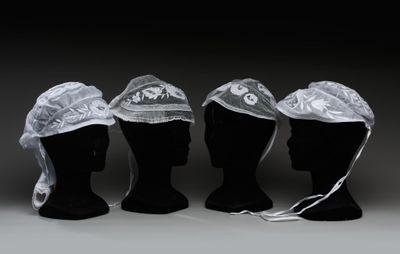 trois têtes de mannequins coiffées de chapeaux dans une pièce sombre