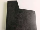 a close up of a piece of black paper on a white surface