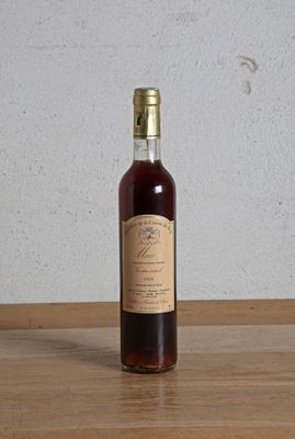 une bouteille de vin posée sur une table, avec un mur blanc en arrière-plan