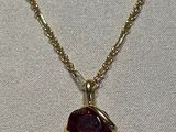 un gros plan d'un collier avec une pierre rouge sur une chaîne en or