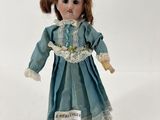 une poupée qui porte une robe bleue et un chapeau