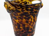 un vase marron et noir muni d'une anse, sur fond blanc