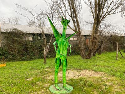 une statue représentant un homme tenant une feuille, assis dans l'herbe