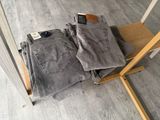 two pairs of grey jeans sitting on top of a wooden chair