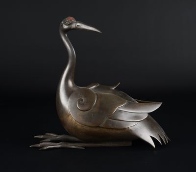 une statue en bronze représentant un oiseau sur fond noir