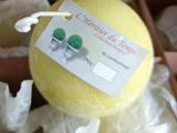 une boule de savon jaune dans une boîte sur laquelle est accrochée une étiquette