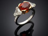 a close up of a ring with a red stone and two white diamonds