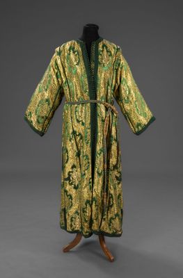 une robe verte et dorée posée sur un présentoir pour mannequin