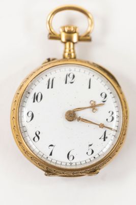 a close up of a gold pocket watch on a white surface