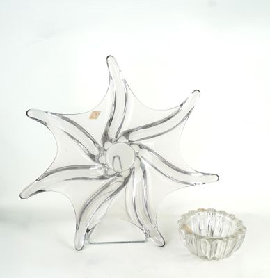 un vase en verre et un bougeoir en verre posés sur une surface blanche