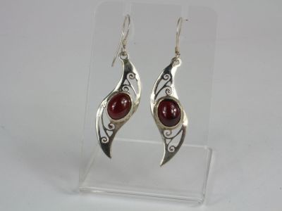 silver and red stone earrings on display in a clear acrylic holder