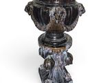 a black vase on a pedestal on a white background