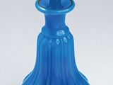 a blue vase with a flower in it on a white surface