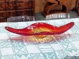 a red glass bowl sitting on a table with a blue and white tablecloth