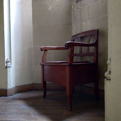une chaise en bois posée dans un coin d'une pièce